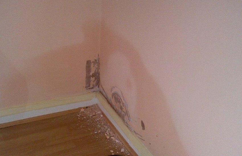 Corner of a room with a hole in the wall with rising damp. 